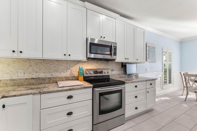 kitchen featuring tasteful backsplash, appliances with stainless steel finishes, white cabinets, and ornamental molding