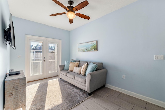 living room featuring a ceiling fan, wood tiled floor, french doors, and baseboards