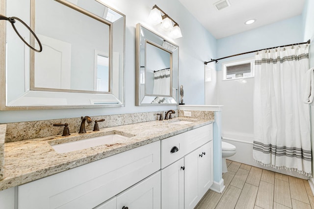 bathroom featuring visible vents, shower / bath combo, a sink, and toilet