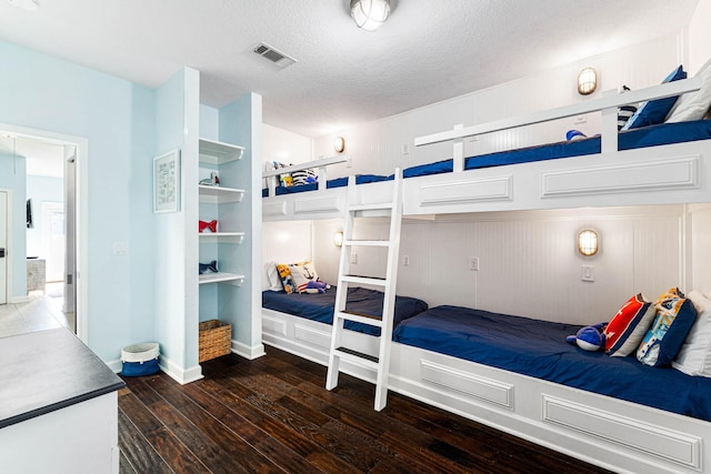 bedroom featuring wood-type flooring, visible vents, and a textured ceiling