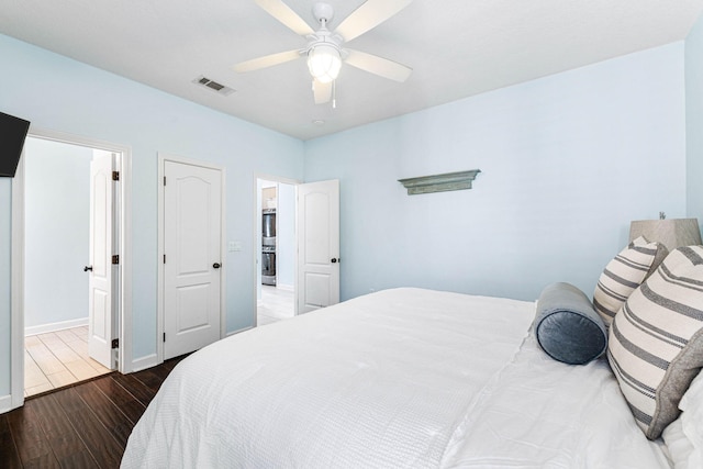 bedroom featuring a ceiling fan, wood finished floors, visible vents, and baseboards