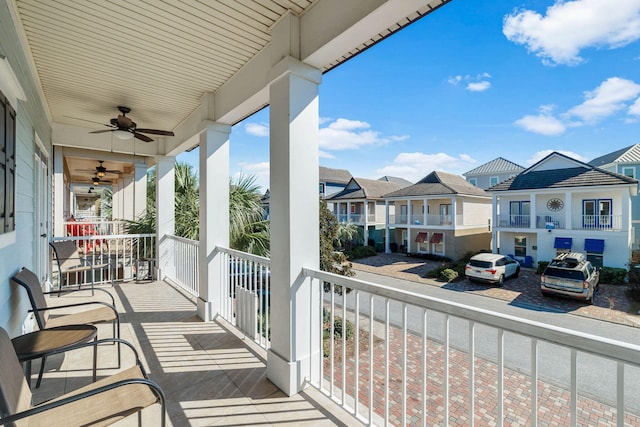 balcony with a sunroom, a residential view, and a ceiling fan