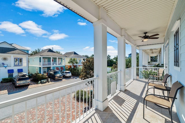 balcony with a sunroom, ceiling fan, and a residential view