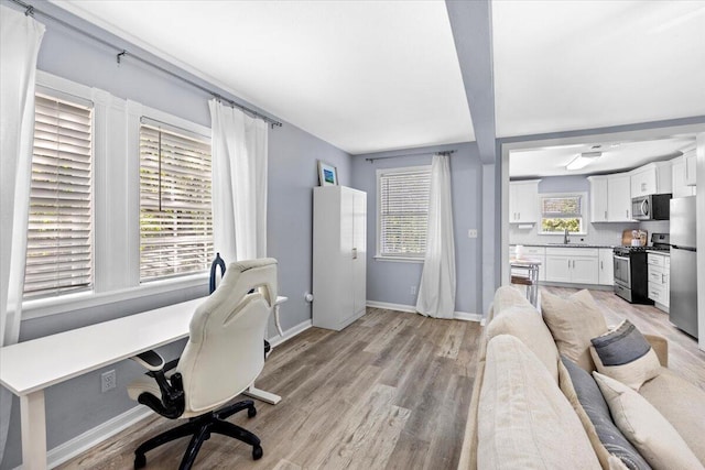 office featuring light wood-style flooring, baseboards, and a sink