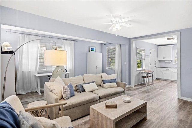 living area with plenty of natural light, light wood-style floors, and a ceiling fan