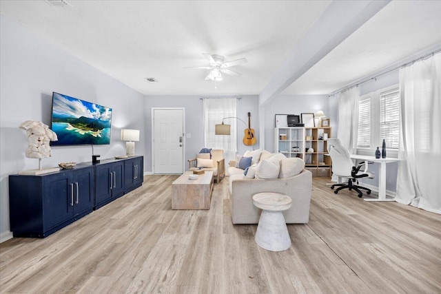 living area featuring light wood finished floors, visible vents, baseboards, and a ceiling fan