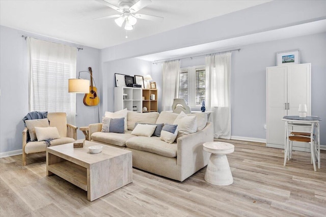 living room with light wood-style flooring, baseboards, and ceiling fan