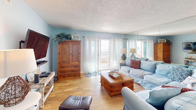 living area featuring visible vents, a textured ceiling, and light wood-style flooring