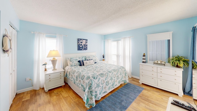 bedroom featuring a textured ceiling, light wood finished floors, and multiple windows