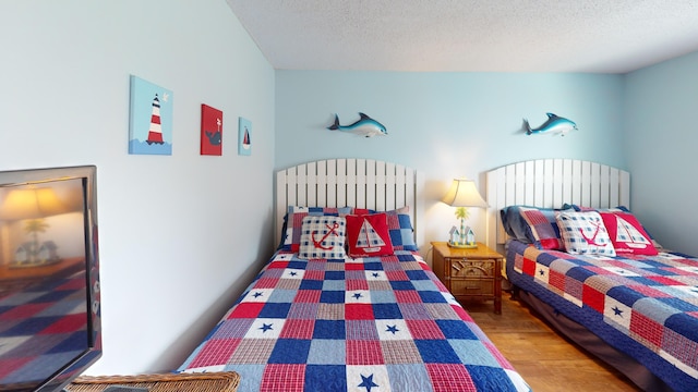 bedroom with a textured ceiling and wood finished floors