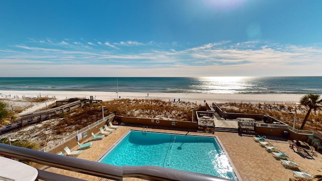 community pool with a view of the beach, a patio area, and a water view