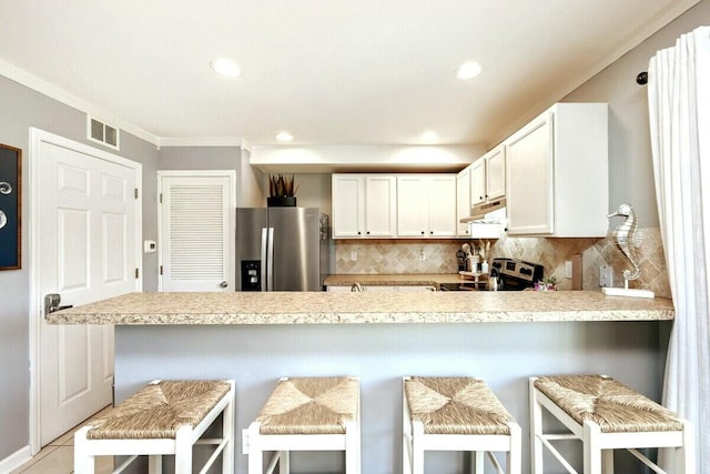 kitchen featuring tasteful backsplash, visible vents, under cabinet range hood, light countertops, and stainless steel appliances