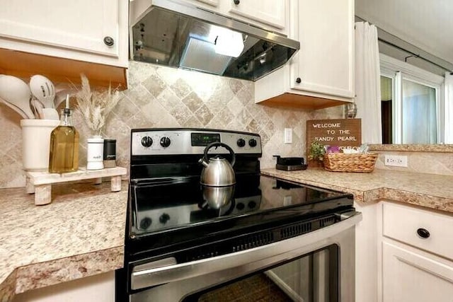 kitchen with under cabinet range hood, stainless steel electric range oven, light countertops, decorative backsplash, and white cabinetry