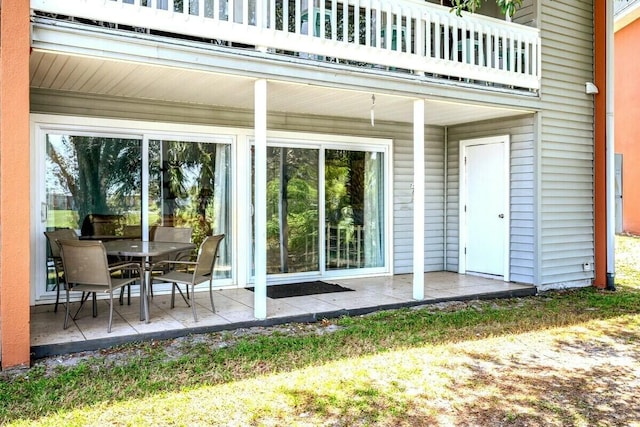 view of exterior entry with a patio and a balcony