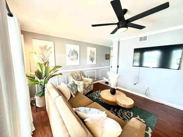 living area with visible vents, baseboards, wood finished floors, and crown molding