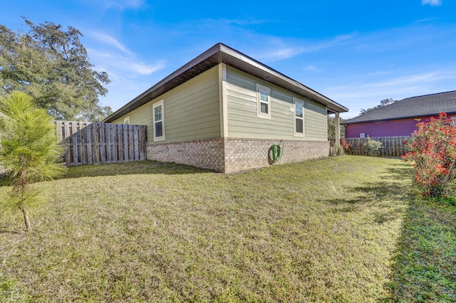 view of property exterior featuring a yard, fence, and brick siding