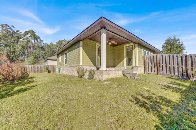 rear view of house featuring brick siding, a lawn, a ceiling fan, entry steps, and a fenced backyard