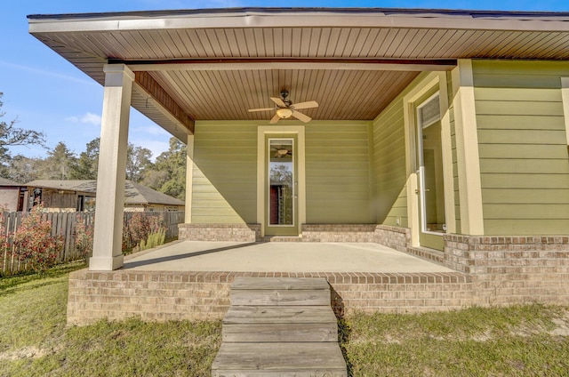 doorway to property featuring brick siding, fence, a patio, and ceiling fan