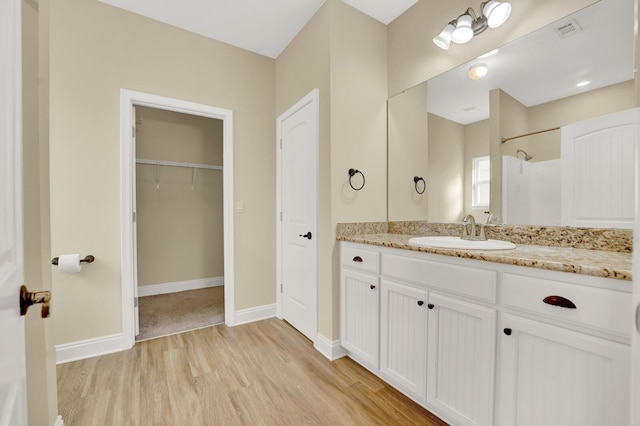 bathroom with vanity, wood finished floors, visible vents, and baseboards