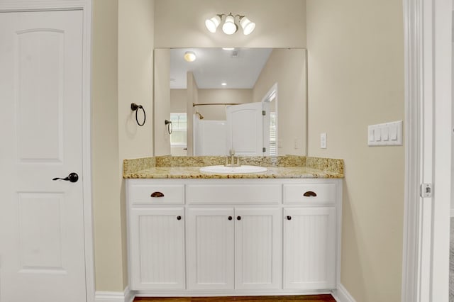 bathroom featuring baseboards, walk in shower, and vanity