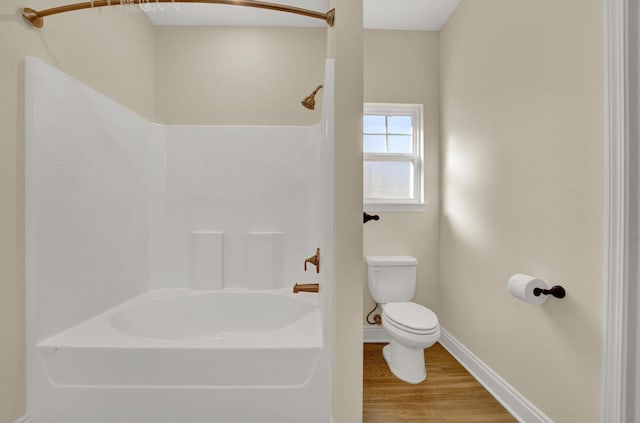 full bath featuring shower / bath combination, wood finished floors, toilet, and baseboards