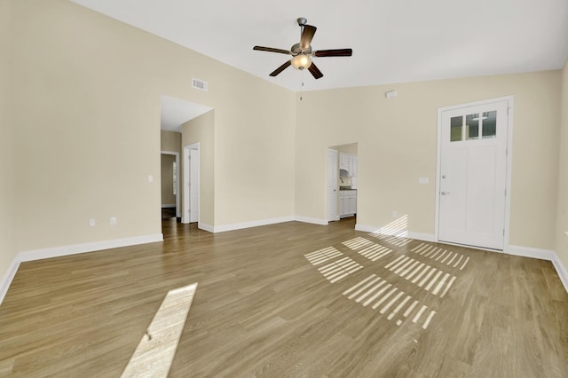 unfurnished living room with a ceiling fan, wood finished floors, visible vents, and baseboards