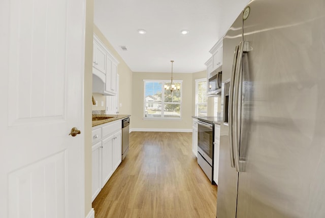 kitchen with appliances with stainless steel finishes, light wood-style flooring, visible vents, and white cabinets