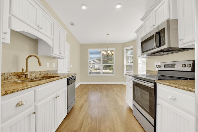 kitchen with a chandelier, stainless steel appliances, a sink, white cabinetry, and light wood finished floors