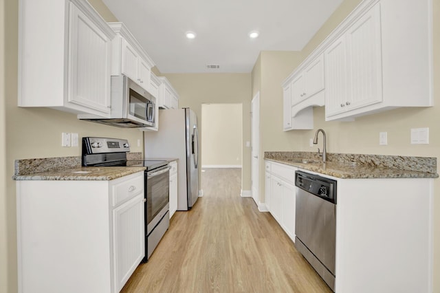 kitchen with stainless steel appliances, a sink, visible vents, white cabinetry, and light wood finished floors