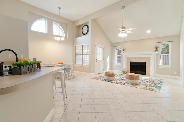 living area with light tile patterned floors, high vaulted ceiling, a fireplace, and plenty of natural light