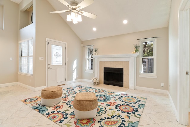 living area featuring a fireplace, ceiling fan, high vaulted ceiling, tile patterned flooring, and baseboards