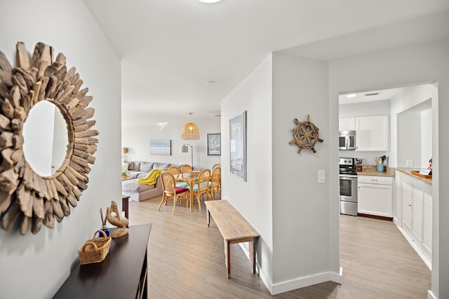 corridor with light wood-style floors and baseboards