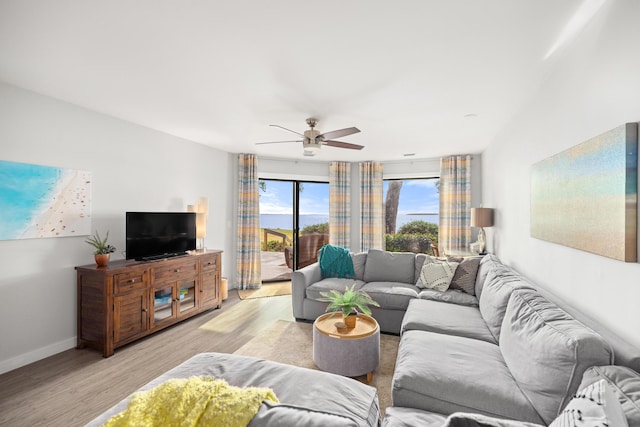 living room featuring ceiling fan, light wood-type flooring, and baseboards