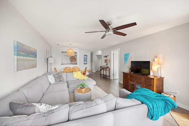 living room featuring ceiling fan, baseboards, and wood finished floors