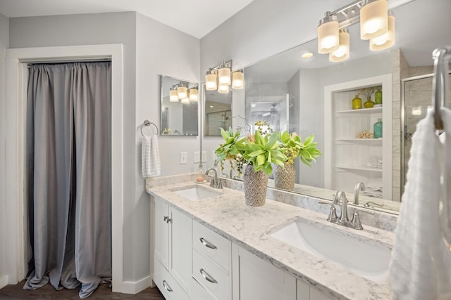 bathroom with a stall shower, a sink, and double vanity