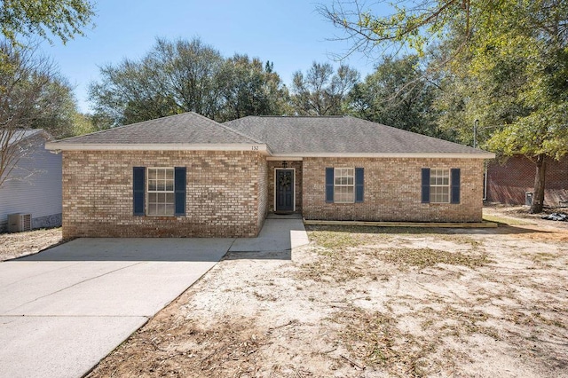 ranch-style house featuring cooling unit, brick siding, and roof with shingles