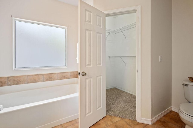 132 Lonnie Jack Dr, Crestview, FL 32536 - bathroom with a walk in closet, baseboards, toilet, a bath, and tile patterned floors