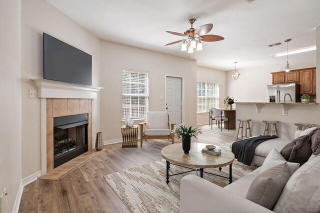 132 Lonnie Jack Dr, Crestview, FL 32536 - living area featuring light wood finished floors, ceiling fan, a tiled fireplace, and baseboards
