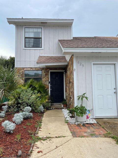 doorway to property featuring a shingled roof