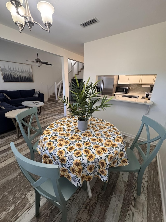 dining area with visible vents, stairway, a ceiling fan, and wood finished floors