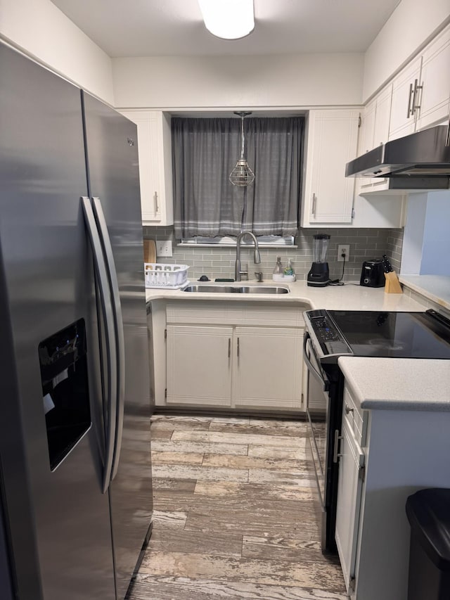 kitchen with under cabinet range hood, light countertops, stainless steel refrigerator with ice dispenser, electric range, and a sink