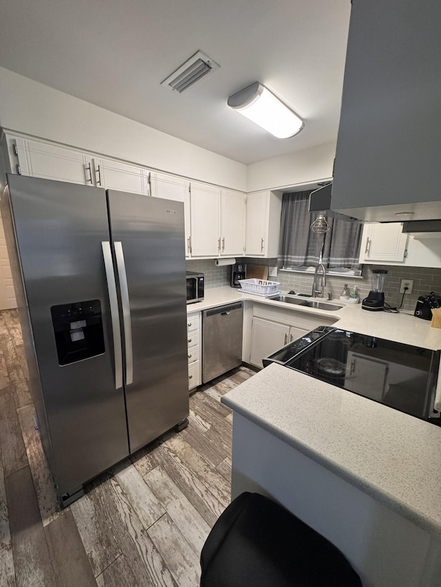 kitchen featuring visible vents, appliances with stainless steel finishes, white cabinetry, and a sink