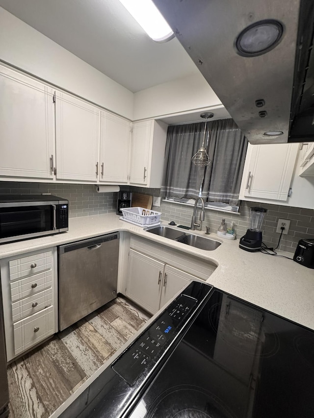 kitchen with a sink, white cabinets, black microwave, and stainless steel dishwasher