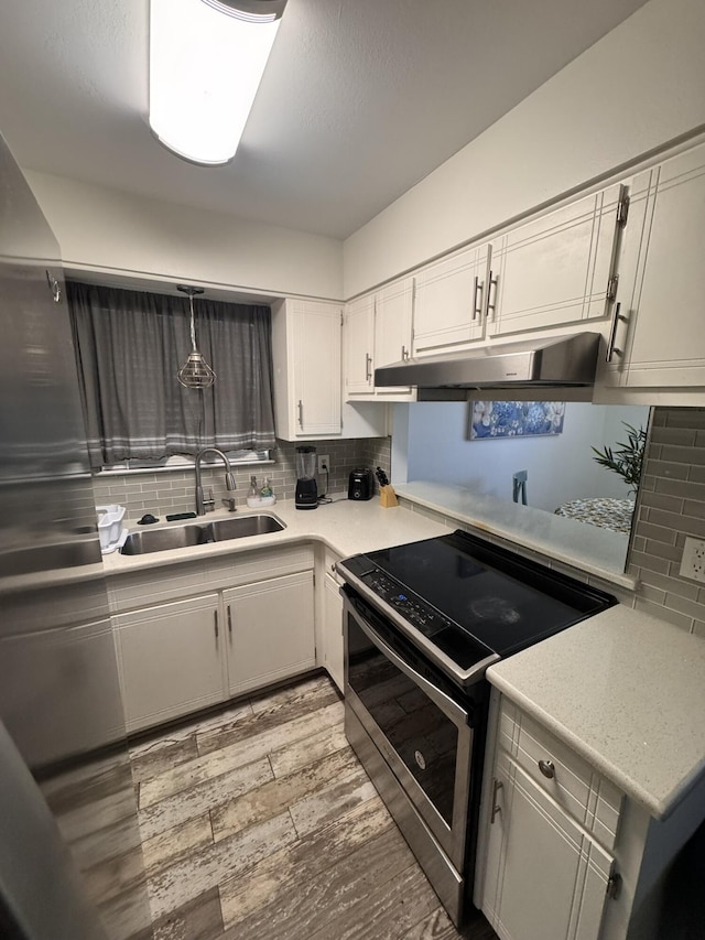 kitchen featuring under cabinet range hood, white cabinetry, stainless steel electric stove, and a sink