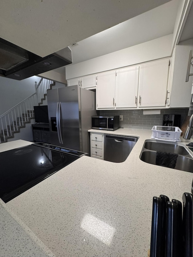 kitchen featuring a sink, decorative backsplash, white cabinetry, and stainless steel appliances