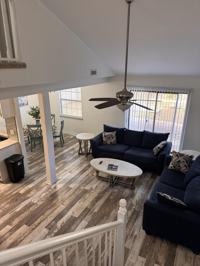 living area with visible vents, wood finished floors, a ceiling fan, and vaulted ceiling