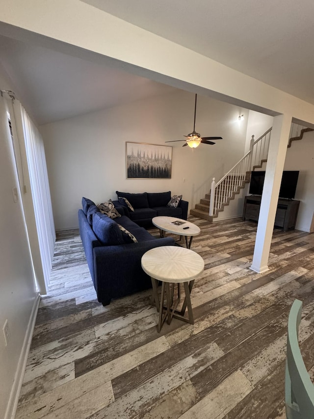 living area featuring stairway, wood finished floors, a ceiling fan, and vaulted ceiling