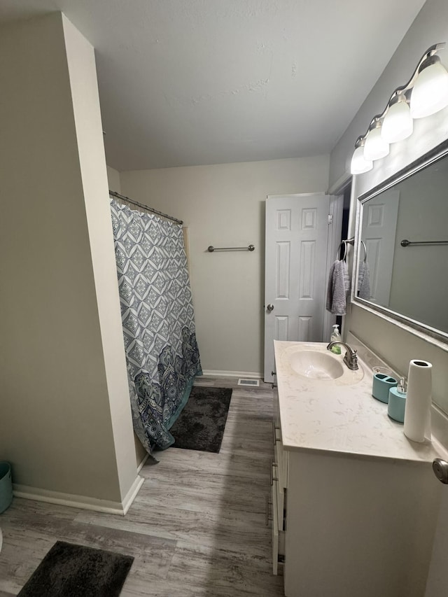 full bathroom with vanity, baseboards, and wood finished floors