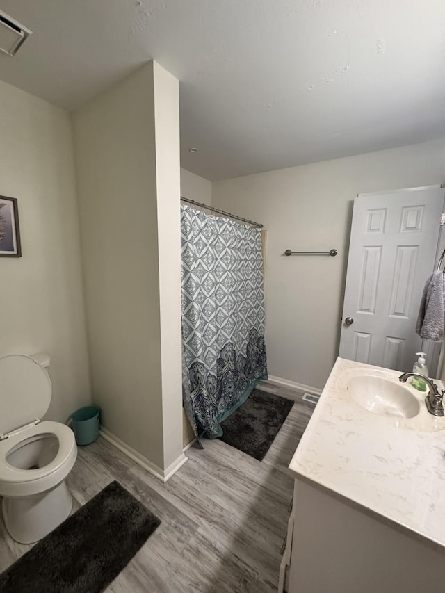 full bath featuring vanity, wood finished floors, visible vents, baseboards, and toilet