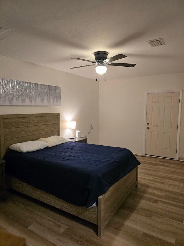 bedroom featuring ceiling fan, visible vents, and wood finished floors